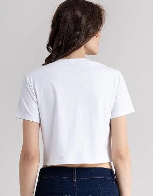 Person wearing a white crop top and dark jeans on a plain background

