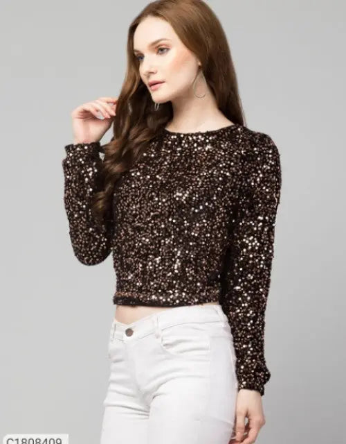 Woman wearing a sequined top and white pants on a gray background