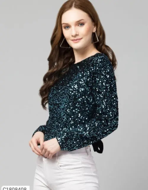 Woman wearing a black sequin top and white pants on a gray background