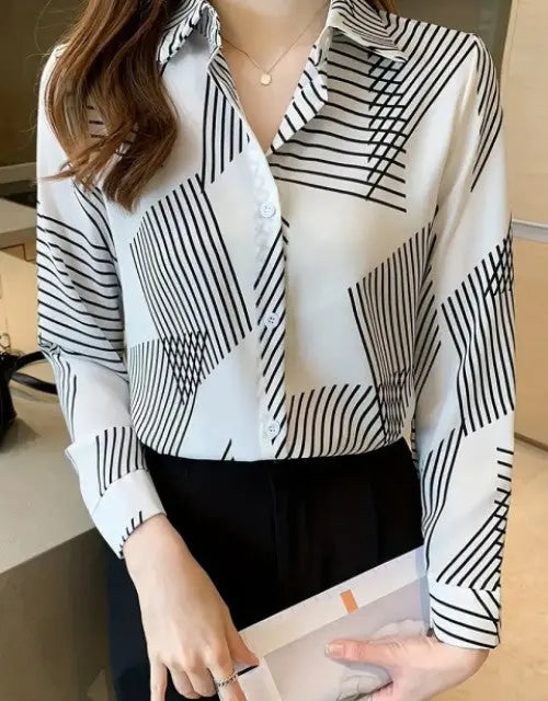 Person wearing a black and white geometric patterned shirt indoors.
