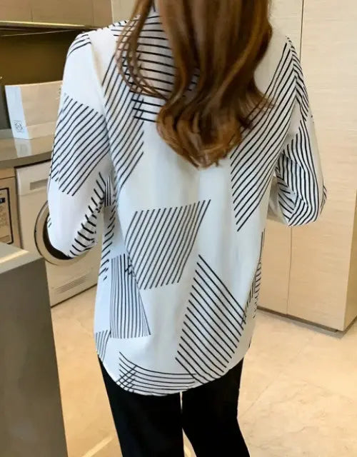 Person wearing a black and white geometric patterned shirt in an indoor setting