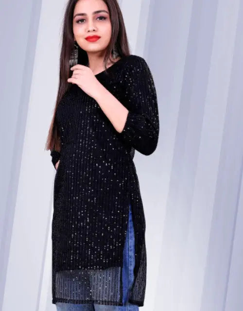 Woman wearing a black sequined dress against a white curtain background