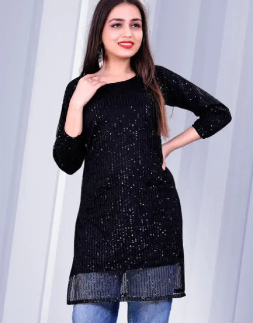 Woman wearing a black sequined dress against a white curtain background