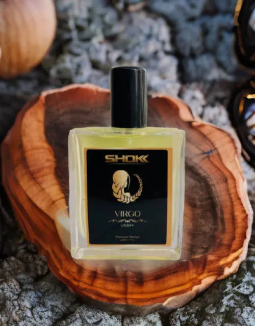 Perfume bottle labeled 'SHOK' on a wooden surface with a blurred natural background

