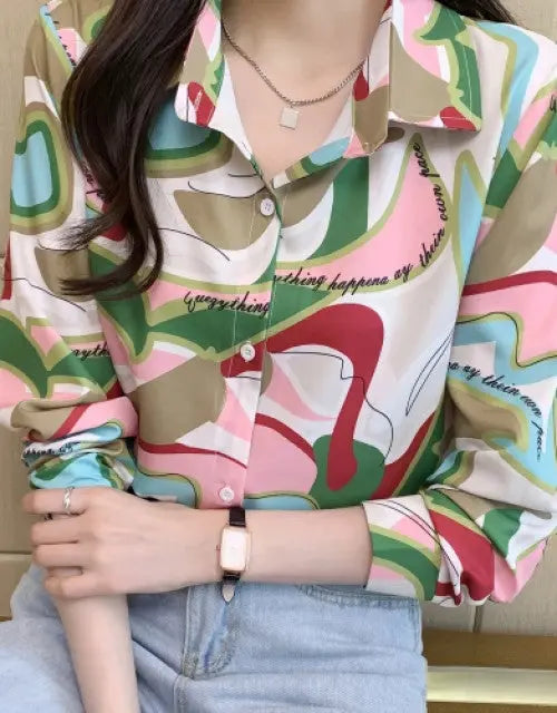 Person wearing a colorful patterned shirt with text, sitting against a neutral background.