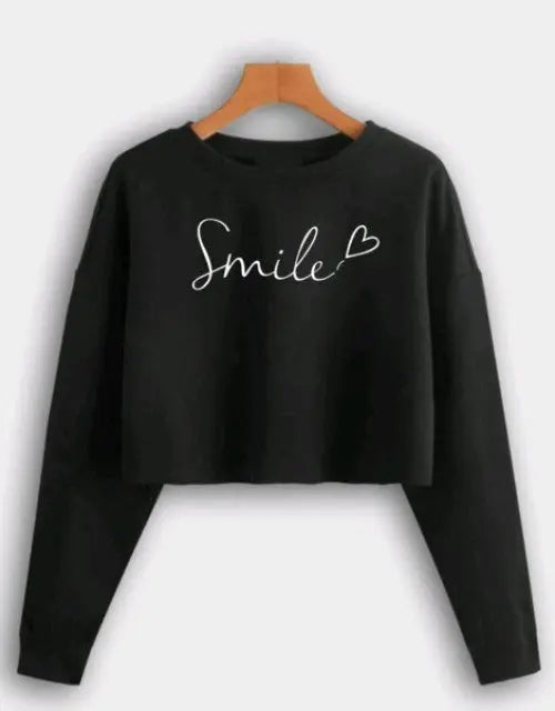 Black long-sleeve crop top with 'Smile' text on a hanger against a white background

