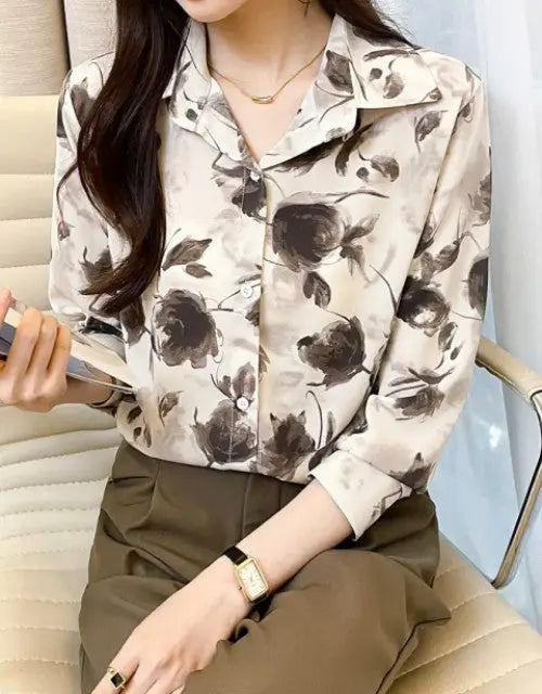 Woman wearing a floral blouse and holding a phone in a casual setting