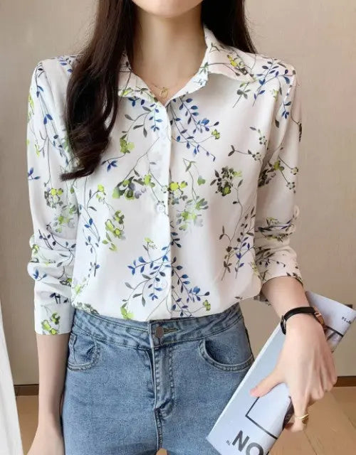 Woman wearing a floral blouse and jeans holding a book.