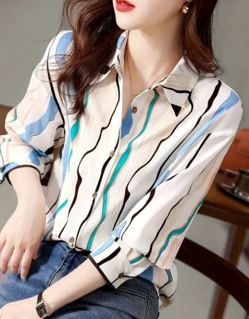 Woman wearing a patterned blouse with blue and black stripes, sitting on a chair.