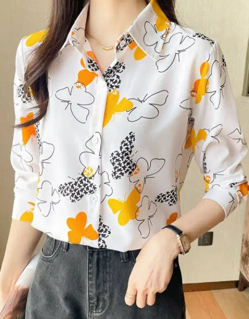Person wearing a white shirt with orange and black floral patterns, standing indoors.