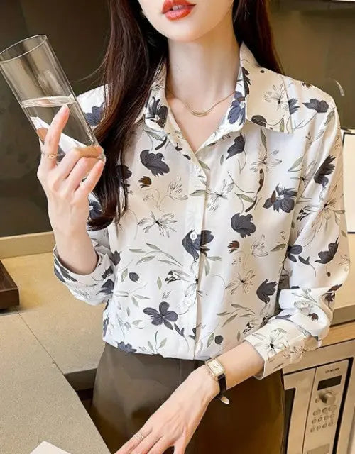 Woman wearing a floral blouse holding a glass in an indoor setting
